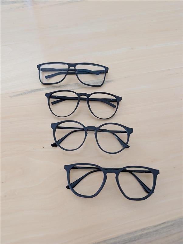 Vier Bubi-Glasses-Fassungen in Schwarz auf einem Holztisch